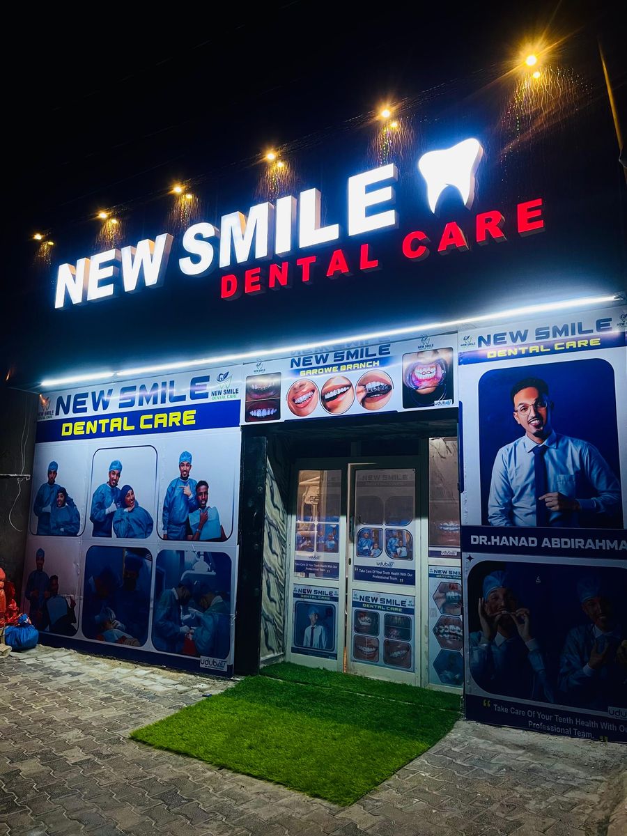 Night view of the illuminated New Smile Dental Care sign and printed clinic facade in Garowe